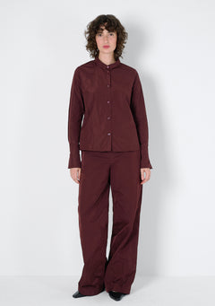 Kastanienfarbene Bluse, mit kleinem kragen und Manschetten an den langen Ärmeln. Die Bluse hat eine leichte A-Form