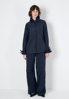 Dunkelblaue Bluse mit einem Blätterkragen und Blättermanschetten, die nach belieben aufgefächert werden können, mit einer verdeckten Knopfleiste.